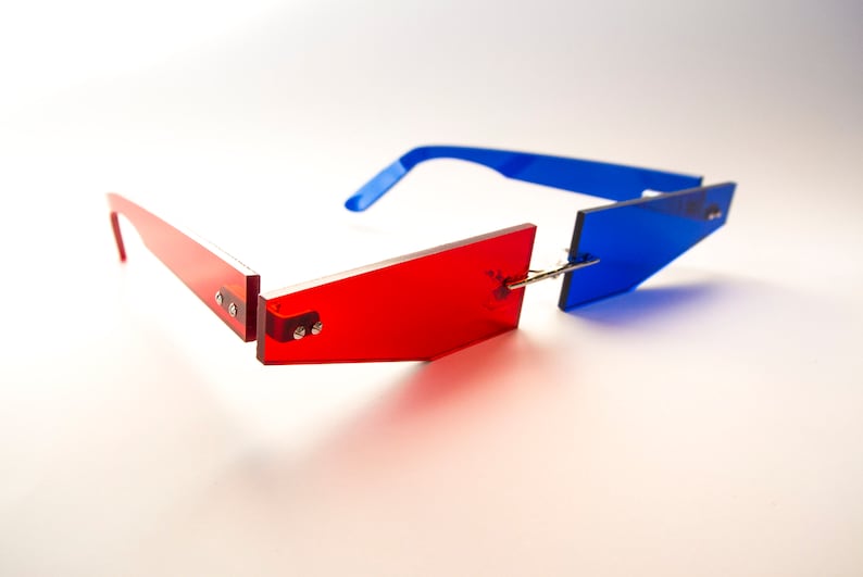 Puede incluir: Un par de gafas de sol rojas y azules con un marco geom&eacute;trico. Las gafas de sol est&aacute;n hechas de pl&aacute;stico y tienen un dise&ntilde;o moderno.