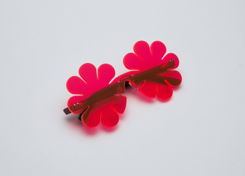 May include: A pair of pink flower-shaped sunglasses with a black frame.