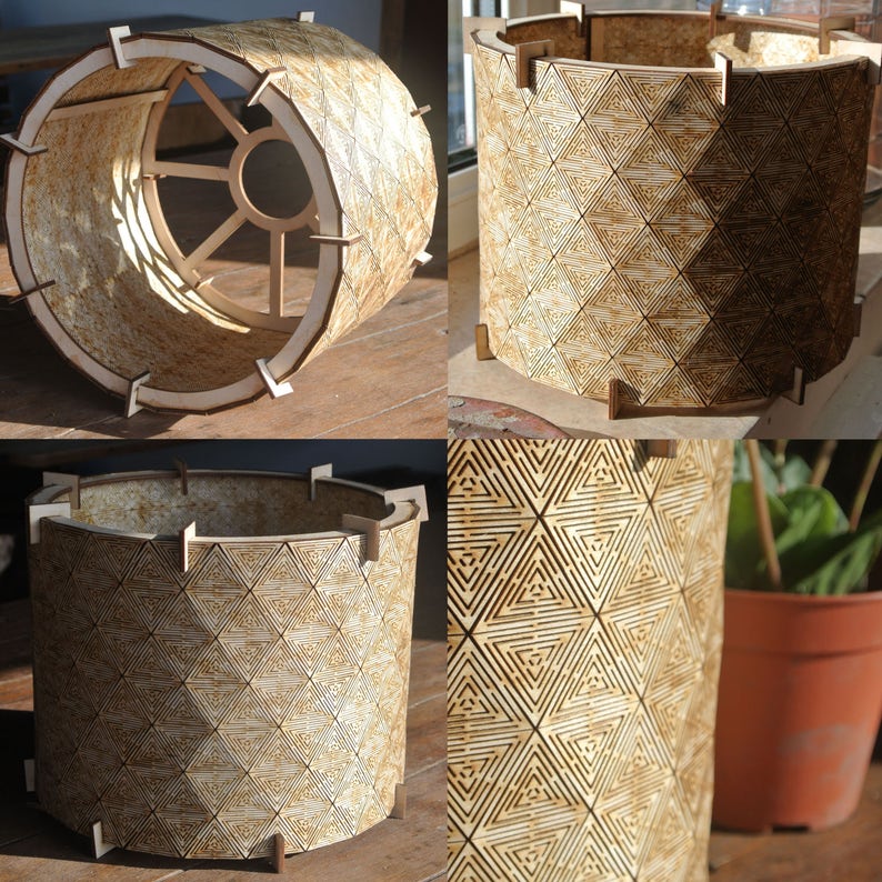 May include: A wooden lampshade with a geometric pattern. The lampshade is made of thin strips of wood that are joined together to create a cylindrical shape. The pattern is made up of triangles that are arranged in a repeating pattern. The lampshade is a light brown color.