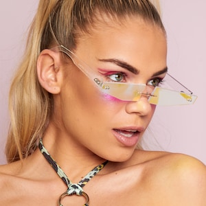 Puede incluir: Una mujer lleva un top halter de estampado de leopardo verde y negro con un anillo dorado. Lleva gafas de sol transparentes e iridiscentes con un marco fino.