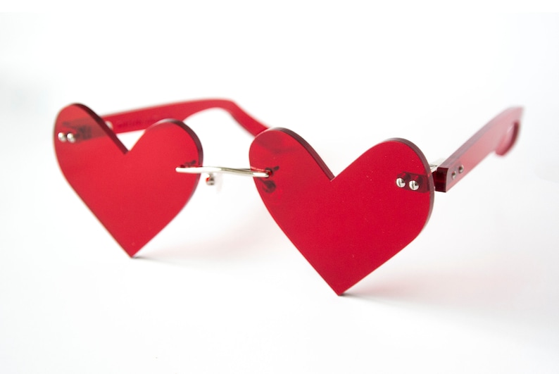 May include: Red heart-shaped sunglasses with a silver bridge and red plastic arms.