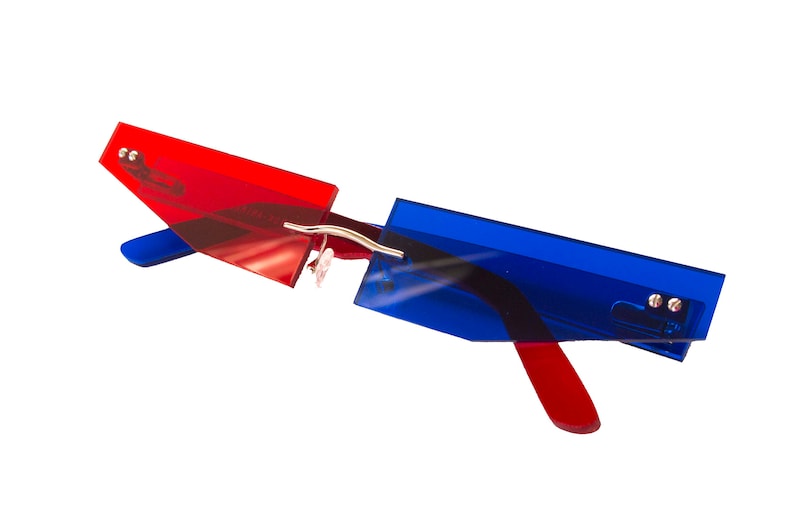 Puede incluir: Gafas de sol tintadas de rojo y azul con un dise&ntilde;o angular &uacute;nico. Las gafas tienen un puente y patillas de metal plateado.