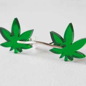 May include: A pair of green marijuana leaf earrings with silver posts.