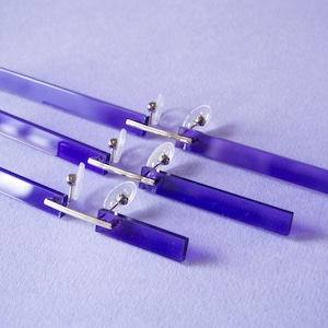 Pode incluir: Três pares de óculos retangulares roxos com dobradiças de metal prateado e hastes de plástico transparente.