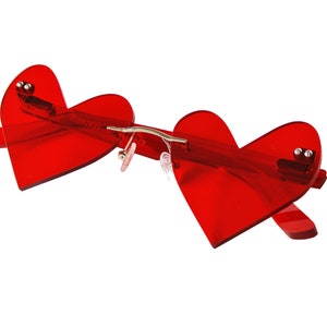 May include: Red heart-shaped sunglasses with a silver metal bridge.