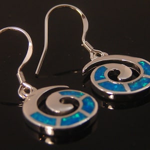 May include: A pair of silver earrings with blue opal swirl designs. The earrings have a hook closure.