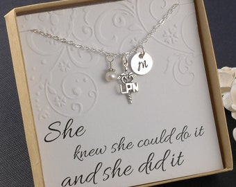 May include: A silver necklace with a pearl charm, a medical symbol charm with the letters "LPN" and a silver disc charm with the letter "M". The necklace is in a box with the text "She knew she could do it and she did it".