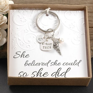 May include: A silver keychain with a charm that says "X-Ray Tech" and a small pearl. The keychain is in a small gift box with a white card that says "She believed she could so she did".