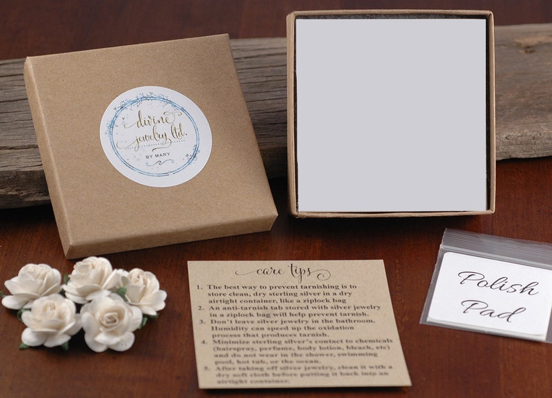 May include: A brown box with a white label that says "dirne jewelry ltd. by mary" and a white box with a white lid. There is a small white card with the text "care tips" and a list of instructions for caring for sterling silver jewelry. There is also a small white bag with the text "Polish Pad".