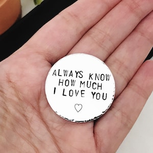 May include: A silver round charm with the text "ALWAYS KNOW HOW MUCH I LOVE YOU" and a small heart symbol.