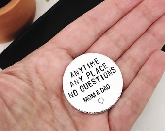 May include: A silver coin with the text "ANYTIME ANY PLACE NO QUESTIONS MOM & DAD" and a small heart symbol.