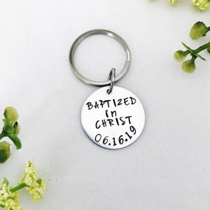 May include: Silver keyring with a round tag that says "Baptized in Christ 06.16.19".