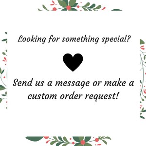 Op de afbeelding: Witte achtergrond met een groene bloemrand. De tekst "Looking for something special?" is geschreven in zwarte cursieve letters. Een zwart hart is gecentreerd onder de tekst. De tekst "Send us a message or make a custom order request!" is geschreven in zwarte cursieve letters onder het hart.