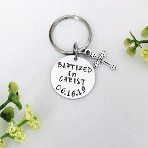 May include: Silver keyring with a round charm that says "Baptized in Christ 06.16.19" and a small silver cross charm.