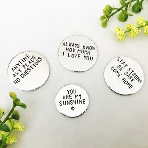 May include: Four silver metal discs with different messages engraved on them. The messages are: "Anytime Any Place No Questions", "Always Know How Much I Love You", "You Are My Sunshine", and "Stay Strong Be Safe Come Home".