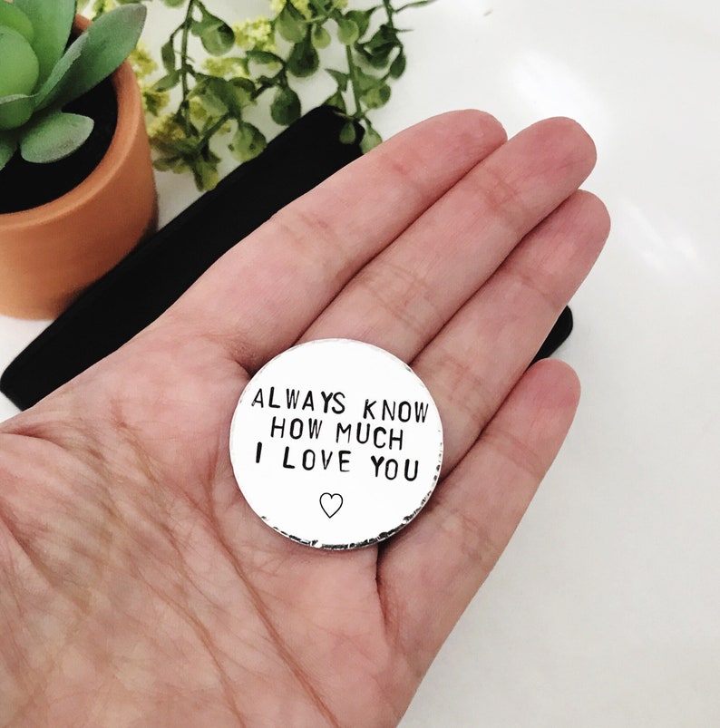May include: A silver round charm with the text "ALWAYS KNOW HOW MUCH I LOVE YOU" and a small heart symbol.