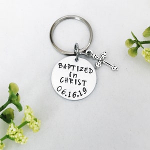 May include: Silver keyring with a round charm that says "Baptized in Christ 06.16.19" and a small silver cross charm.