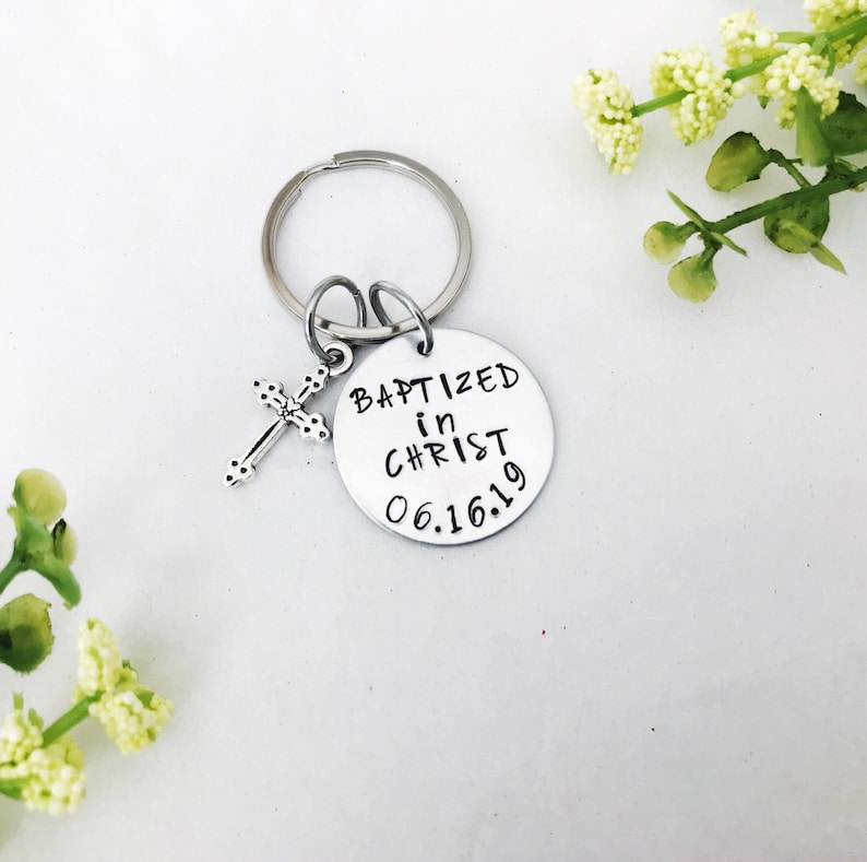 May include: Silver keyring with a small cross charm and a round tag that reads "Baptized in Christ 06.16.19".