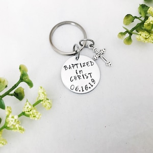 May include: Silver keyring with a round charm that says "Baptized in Christ 06.16.19" and a small silver cross charm.