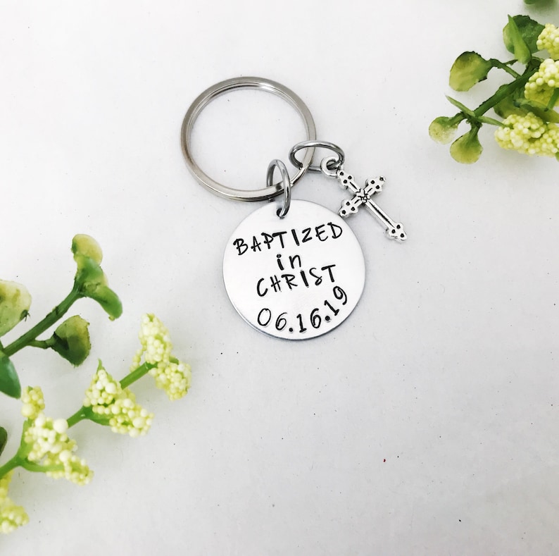 May include: Silver keyring with a round charm that says "Baptized in Christ 06.16.19" and a small silver cross charm.