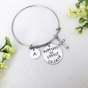 Puede incluir: Pulsera de brazalete de plata con un dije de cruz, un dije con la letra A y un dije que dice "Bautizado en Cristo 06.16.19".