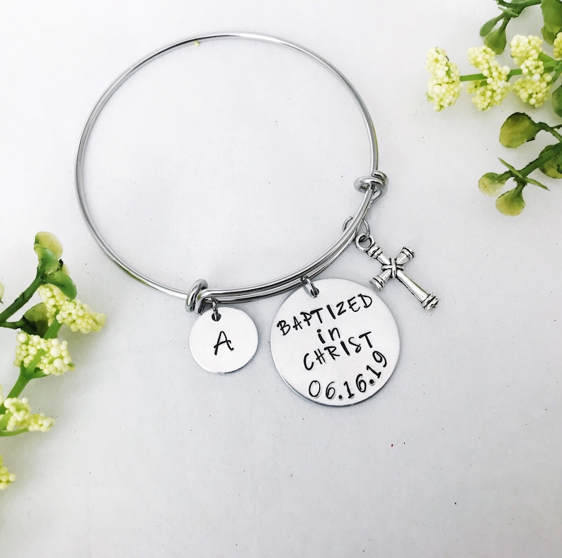 Puede incluir: Pulsera de brazalete de plata con un dije de cruz, un dije con la letra A y un dije que dice "Bautizado en Cristo 06.16.19".