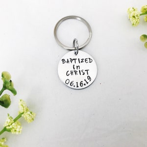 May include: Silver keyring with a round tag that says "Baptized in Christ 06.16.19".