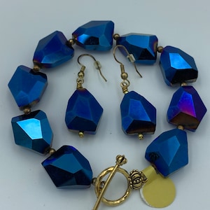 Peut inclure: Un collier et des boucles d'oreilles assortis en cristal bleu avec des accents dor&eacute;s. Le collier a un fermoir &agrave; bascule.