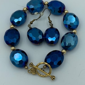 May include: A blue crystal bracelet and matching earrings with gold accents. The bracelet has a toggle clasp.