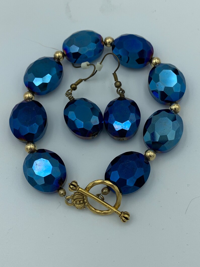 May include: A blue crystal bracelet and matching earrings with gold accents. The bracelet has a toggle clasp.