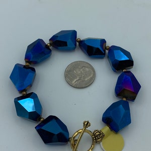 Peut inclure: Un bracelet en cristal bleu avec un fermoir et un charme en or. Le bracelet est compos&eacute; de cristaux facet&eacute;s iris&eacute;s.