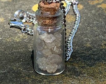 Collar con colgante de cuarzo transparente crudo en una botella