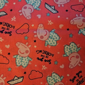 May include: Pink fabric with a repeating pattern of a cartoon pig wearing pajamas, stars, hearts, and paper boats. The text "Sea you in the morning" is repeated throughout the fabric.