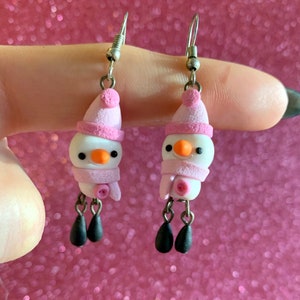 Pendientes navideños de muñeco de nieve rosa con patas colgantes, hechos a mano en arcilla polimérica.