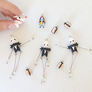 May include: A set of nine handmade polymer clay charms featuring characters from the Nightmare Before Christmas. The set includes Jack Skellington, Sally, Zero the dog, and a variety of gift box charms. The charms are perfect for adding a spooky touch to your jewelry or crafts.
