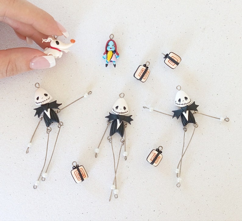 May include: A set of nine handmade polymer clay charms featuring characters from the Nightmare Before Christmas. The set includes Jack Skellington, Sally, Zero the dog, and a variety of gift box charms. The charms are perfect for adding a spooky touch to your jewelry or crafts.