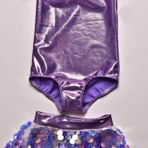 May include: A purple leotard with short, ruffled sleeves and a matching sequined skirt. The skirt has a white lining and iridescent sequins.