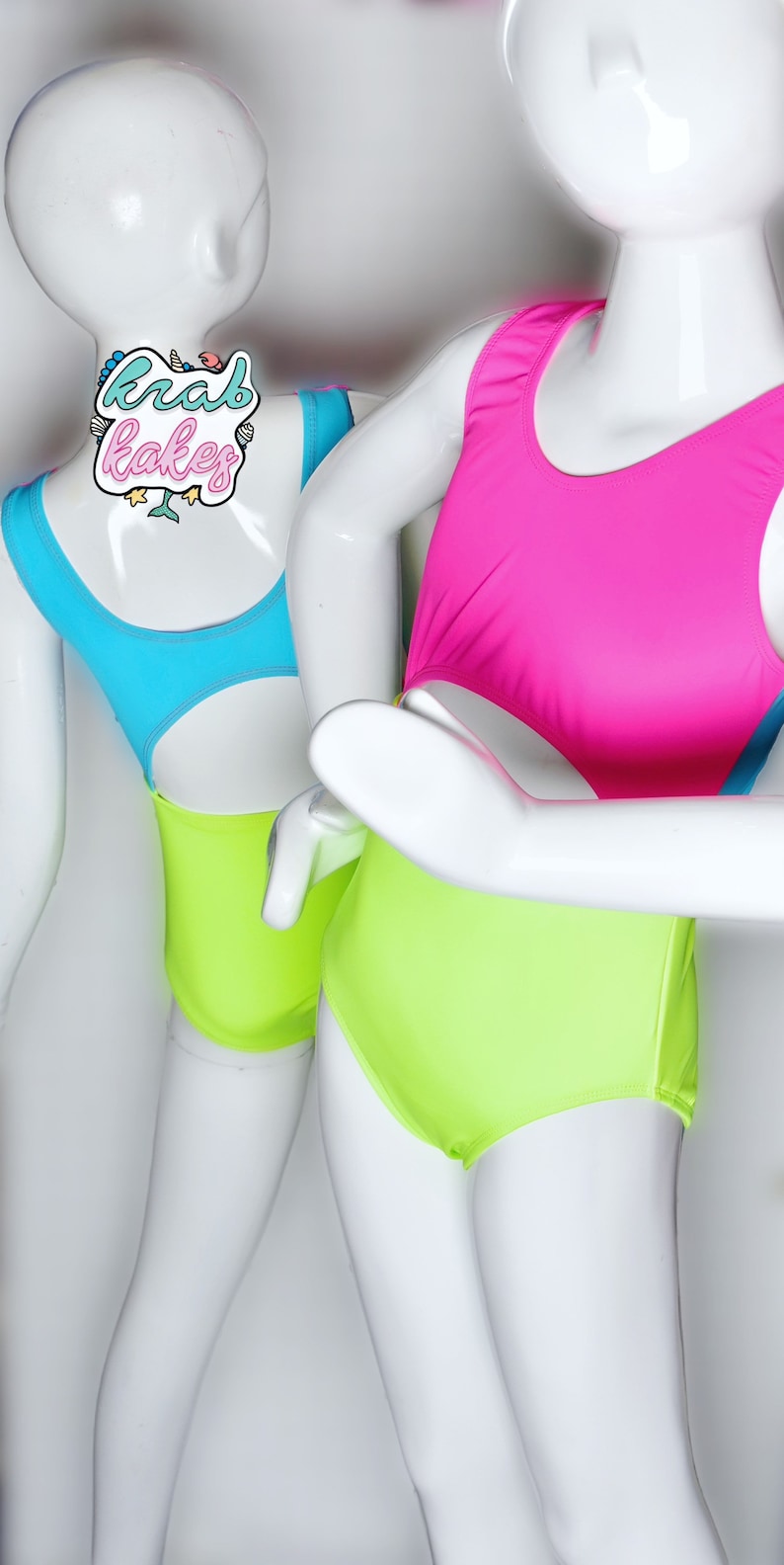 May include: Two mannequins wearing bright neon leotards. The leotard on the left is turquoise and lime green. The leotard on the right is hot pink and lime green.