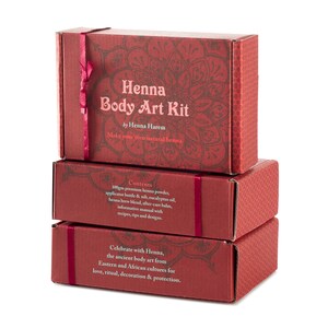 May include: Three red boxes stacked on top of each other. The top box has a red ribbon and says "Henna Body Art Kit by Henna Harem Make your own natural henna". The middle box says "Contents 100gm premium henna powder, applicator bottle & nib, eucalyptus oil, henna brew blend, after care balm, informative manual with recipes, tips and designs.". The bottom box says "Celebrate with Henna, the ancient body art from Eastern and African cultures for love, ritual, decoration & protection."