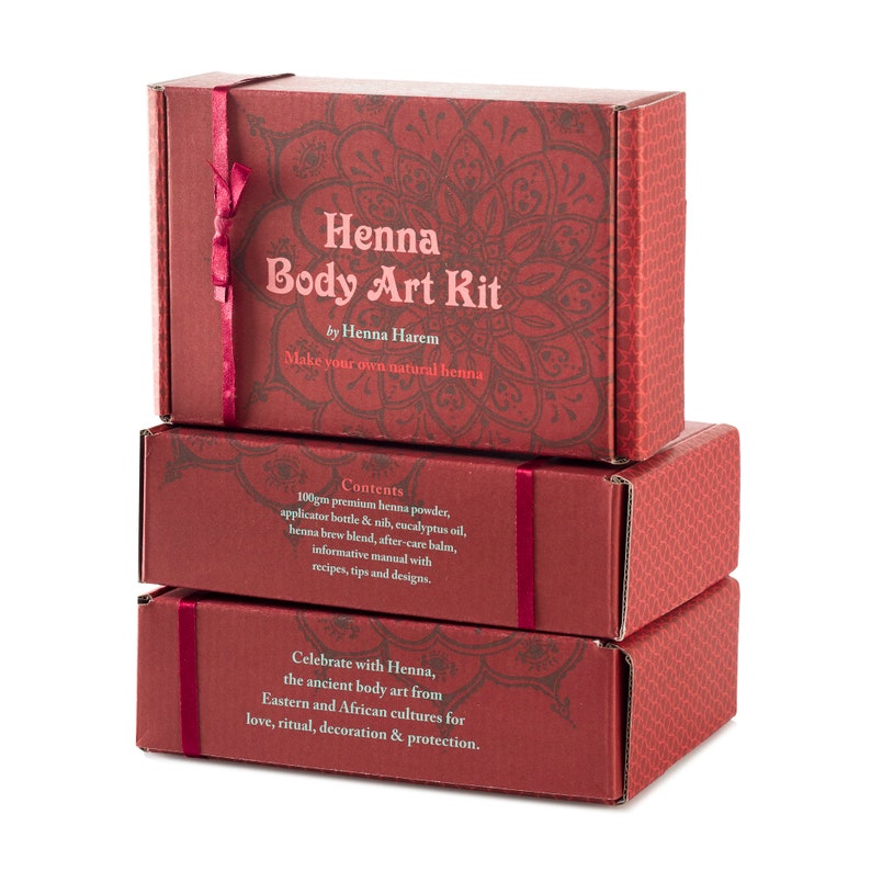 May include: Three red boxes stacked on top of each other. The top box has a red ribbon and says "Henna Body Art Kit by Henna Harem Make your own natural henna". The middle box says "Contents 100gm premium henna powder, applicator bottle & nib, eucalyptus oil, henna brew blend, after care balm, informative manual with recipes, tips and designs.". The bottom box says "Celebrate with Henna, the ancient body art from Eastern and African cultures for love, ritual, decoration & protection."