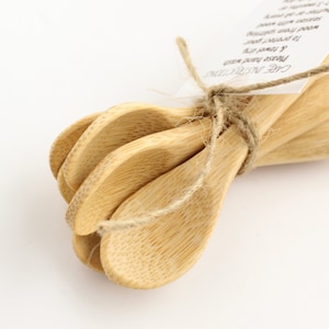 May include: A set of four small wooden spoons tied together with twine. The spoons are made of natural bamboo and have a smooth, rounded shape.