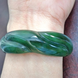 Può includere: Un braccialetto di giada verde con un design a spirale ondulato.