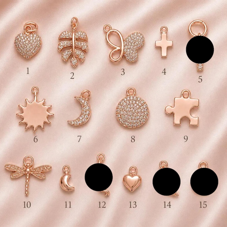 May include: A collection of fifteen rose gold-toned metal charms featuring various shapes including a heart, leaf, butterfly, cross, sun, crescent moon, circle, puzzle piece, and dragonfly, some encrusted with small clear stones and numbered 1 to 15.