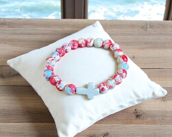 Pulsera elástica con cruz de cuentas rosa fucsia y azul claro