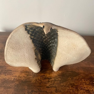 Könnte beinhalten: Eine Keramikskulptur eines Vogels mit ausgebreiteten Flügeln. Die Skulptur ist in Weiß-, Braun- und Schwarztönen bemalt.