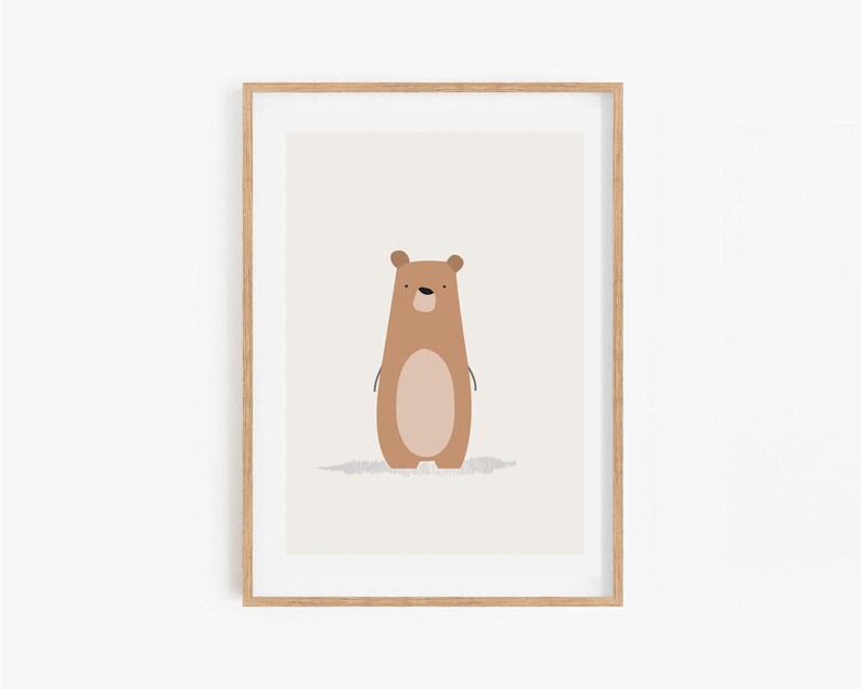 May include: A framed art print featuring a cartoon bear illustration. The bear is brown with a lighter brown oval belly and a small shadow. The artwork is set against a light beige background, framed in a natural wood frame.