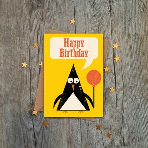 Op de afbeelding: Een gele verjaardagskaart met een pingu&iuml;n die een rode ballon vasthoudt. De kaart zegt "Happy Birthday" in een spreekballon.