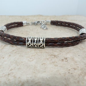 May include: A brown leather bracelet with silver beads and a braided design.