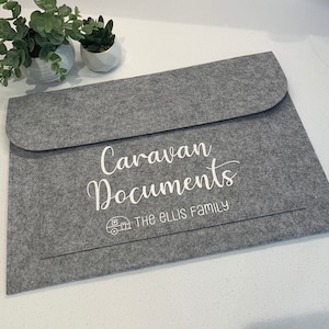 May include: Grey felt folder with the text "Caravan Documents" and "THE ELLIS FAMILY" in white lettering. A small white icon of a caravan is above the family name.