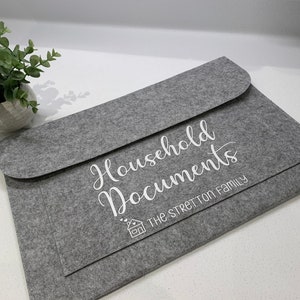 May include: Grey felt folder with the text "Household Documents" and "The Stretton Family" in white lettering. A small house icon is also printed on the folder.